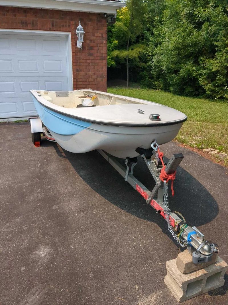 Small family boat on a trailer in a home driveway, ready for boat detailing in Indianapolis